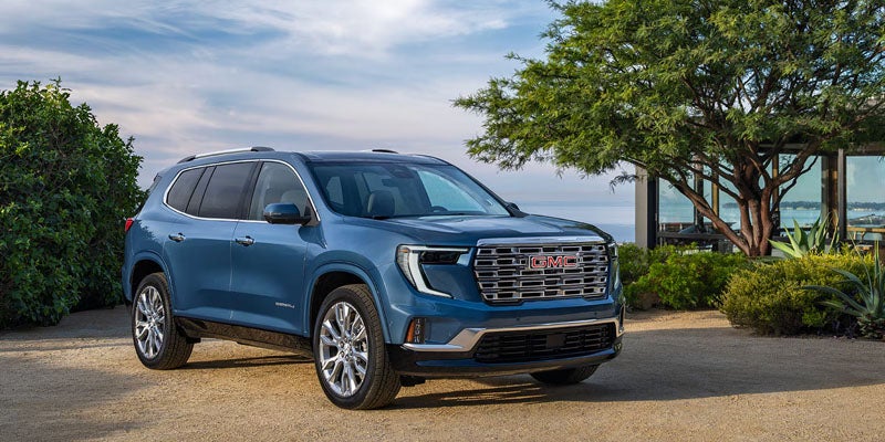 Blue 2026 GMC Acadia parked outdoors near trees