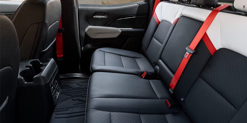 2026 GMC Canyon interior featuring premium rear seating with black upholstery and red seat belts