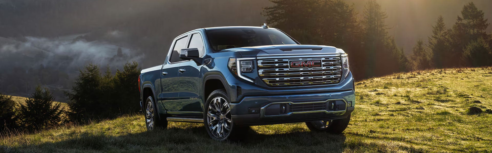 2026 GMC Sierra 1500 blue vehicle on forested country hillside