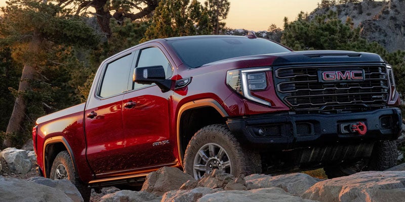 Red 2026 GMC Sierra 1500 off-roading on rocky terrain showcasing strong capability and rugged performance.