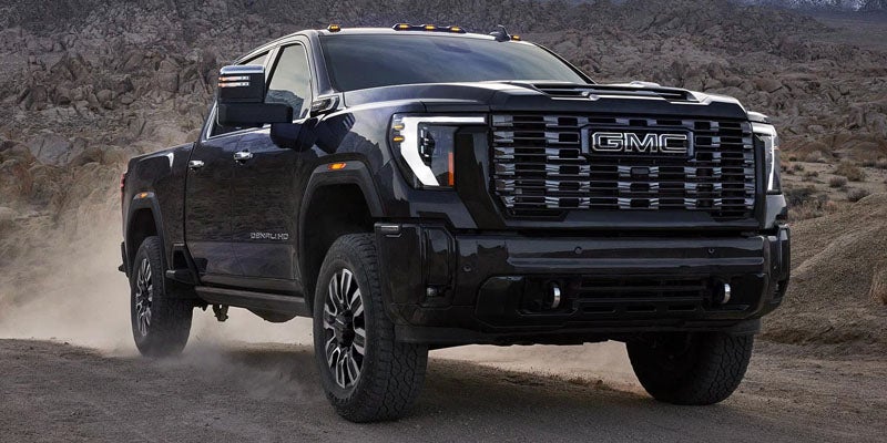 2026 GMC Sierra 2500 HD heavy-duty pickup truck driving on a rugged desert trail.