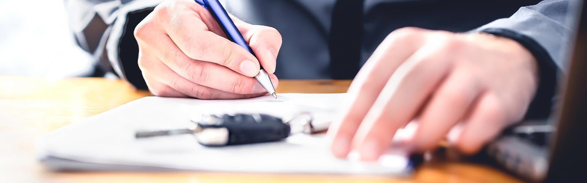 Customer signing auto financing paperwork at a dealership.